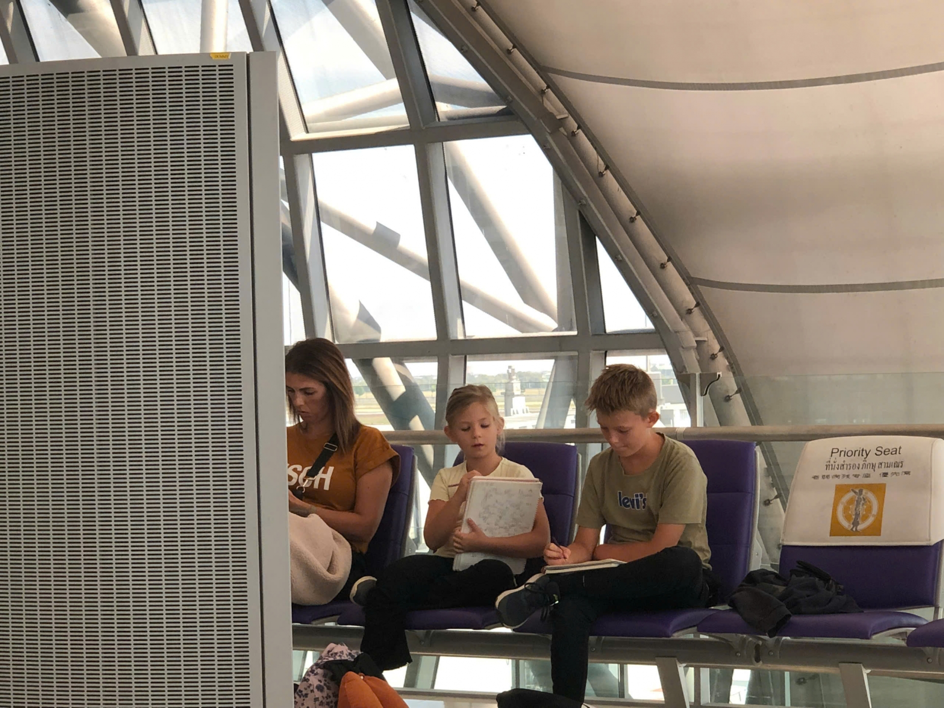 2 bạn nhỏ đang vẽ trong khi ngồi đợi máy bay ở Băng Cốc, Thái Lan (Cô Sim chụp trong chuyến đi Thái Lan năm 2023)